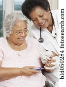 Doctor testing African American woman’s blood sugar