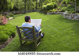 Hispanic man reading in backyard