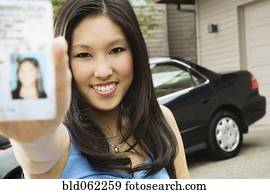 Asian teenager proudly showing new driver’s license