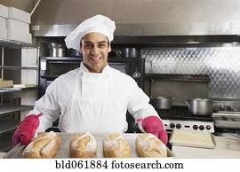 Hispanic male baker holding tray of fresh bread