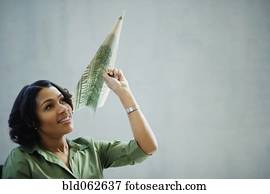 African businesswoman holding money paper airplane