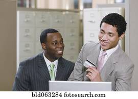 Multi-ethnic businessmen with laptop holding credit card