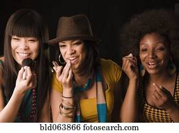 Multi-ethnic women putting on makeup