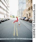 Hispanic teenage boy doing back flip in urban street