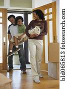 African mother and father carrying carpet and son into new home