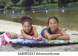 Friends laying on boogie board near lake