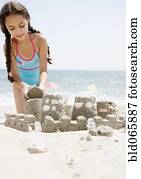 Hispanic girl building sand castle on beach