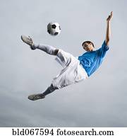 Mixed race teenager in mid-air kicking soccer ball