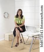 Hispanic businesswoman sitting on office desk
