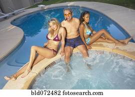 Playboy enjoying hot tub with young girlfriends