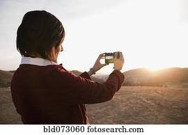 Hispanic woman photographing the sunset