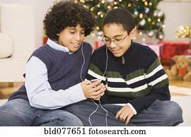 Hispanic brothers sharing mp3 player at Christmas