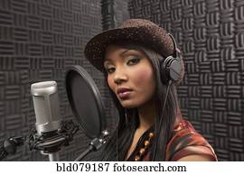 Mixed race woman singing in recording studio