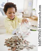 Black boy emptying jar of coins on table