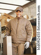 Smiling Hispanic delivery man holding cardboard box