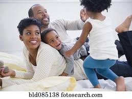 Black family laying on bed together