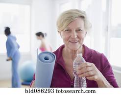 Caucasian woman with yoga mat drinking water