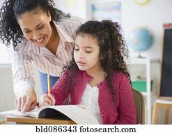 Teacher helping girl with school work in classroom