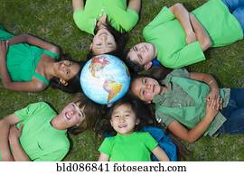 Children laying in grass around globe