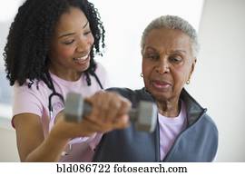 Nurse helping woman exercise with dumbbell