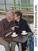 Senior Hispanic couple kissing in cafe