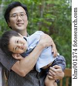 Asian father carrying son