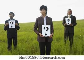 Businesspeople holding question marks in field