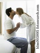 Hispanic couple kissing in bedroom