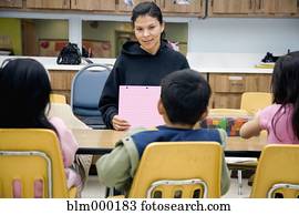 Hispanic teacher sitting at table with students