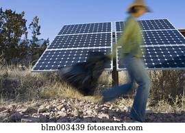 Native American woman carrying bag past solar panels