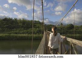 Rear view of woman walking on wooden footbridge