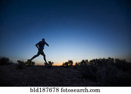 Silhouette of Caucasian teenage boy running at dawn