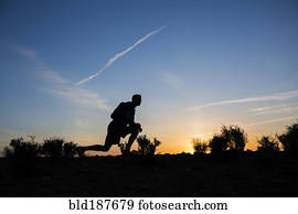 Silhouette of Caucasian teenage boy running at dawn