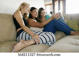 Women taking self-portrait together on sofa