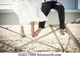 Asian bride and groom sitting on lifeguard hut on beach