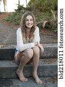 Barefoot girl sitting on park steps