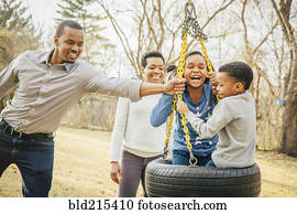 Black family playing on tire swing