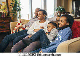 Black family watching television on sofa
