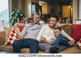 Black family watching television on sofa