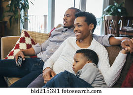 Black family watching television on sofa