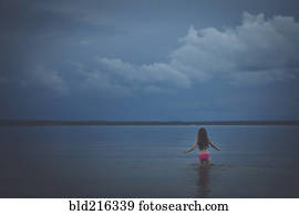 Caucasian girl wading in remote lake