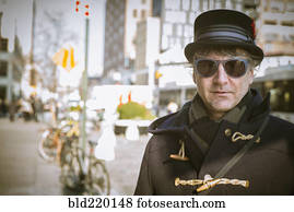 Caucasian man in top hat standing on city sidewalk
