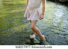 Girl standing barefoot in pond