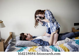 Woman photographing boyfriend on bed
