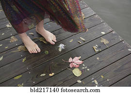 Woman standing barefoot on wooden dock