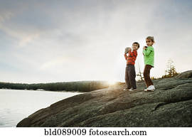 Children holding rocks near remote lake