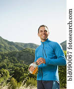 Athletic mixed race man drinking water outdoors