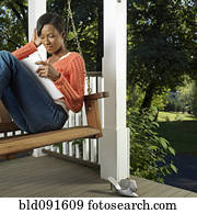 Mixed race woman reading on porch