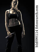 Serious athletic woman in sportswear holding water bottle