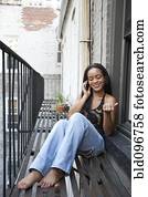 African American woman using cell phone on fire escape